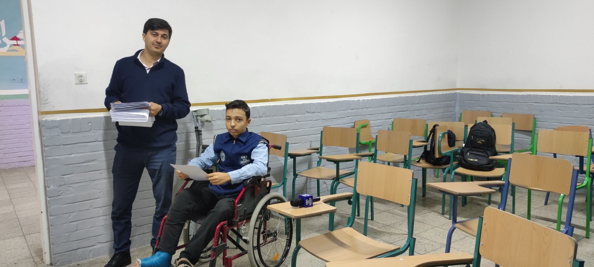 دانش آموز خبرنگار خبرگزاری پانا نشسته بر صندلی چرخدار در پای آزمون نوبت اول